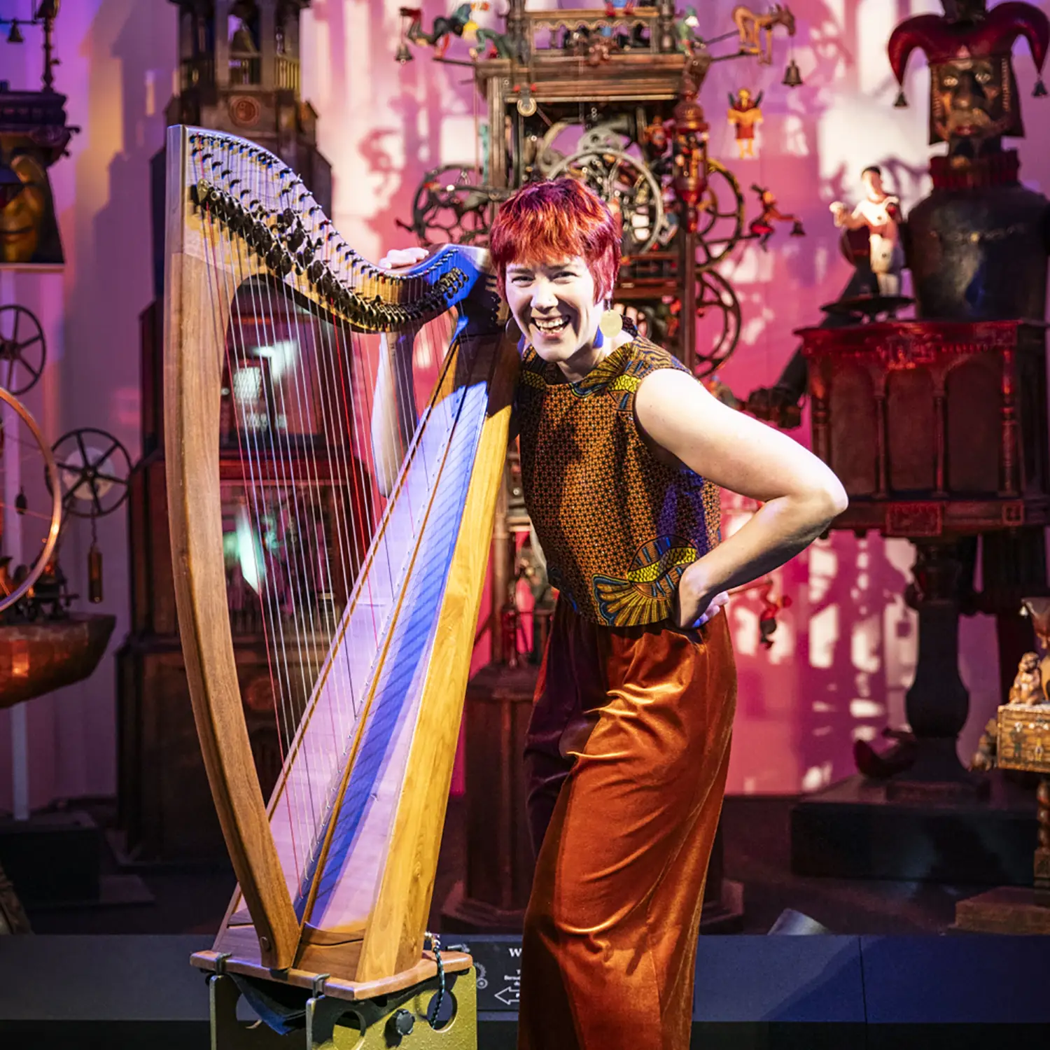 Harp player laughing in front of colourful background